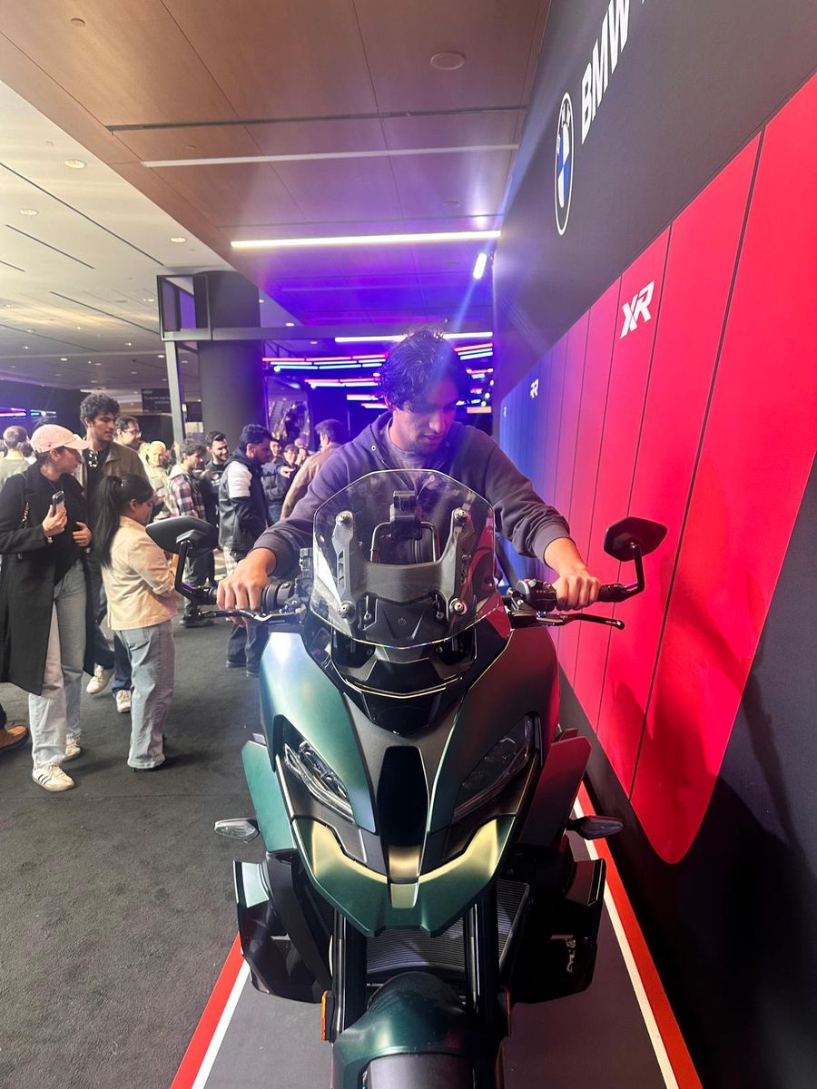Sitting on a touring motorcycle at a motor show stand under red and blue lights.