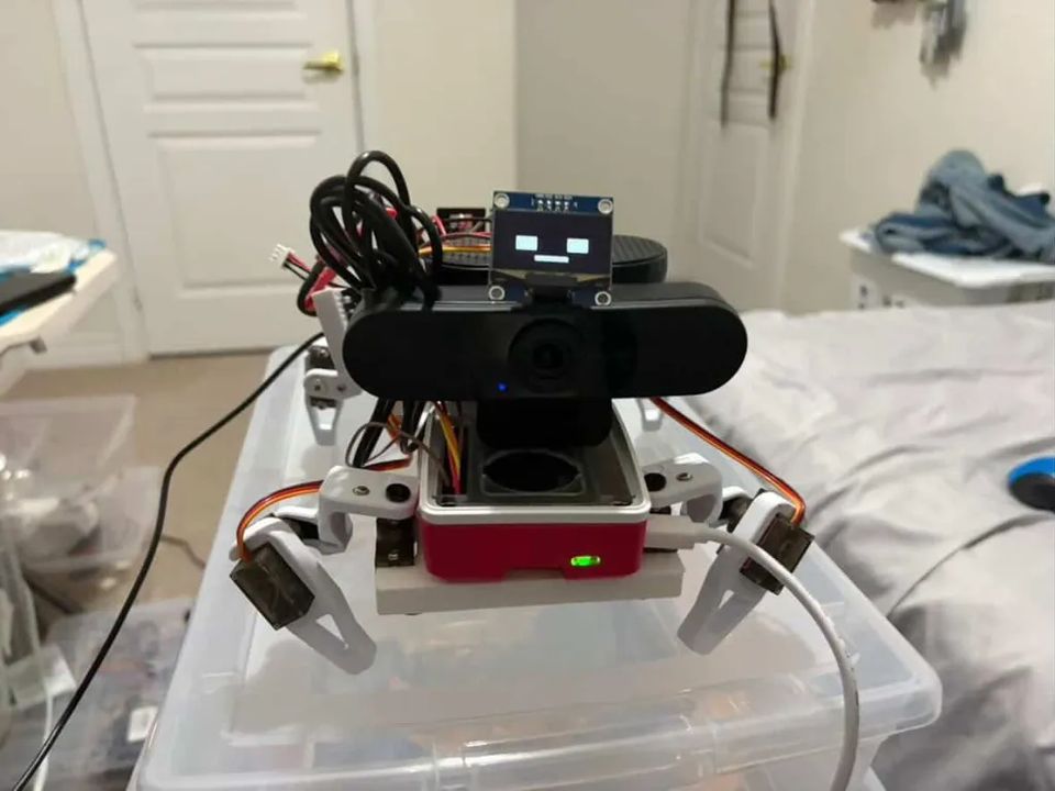 The finished robot photographed head on, webcam centred and the OLED face showing two square eyes.
