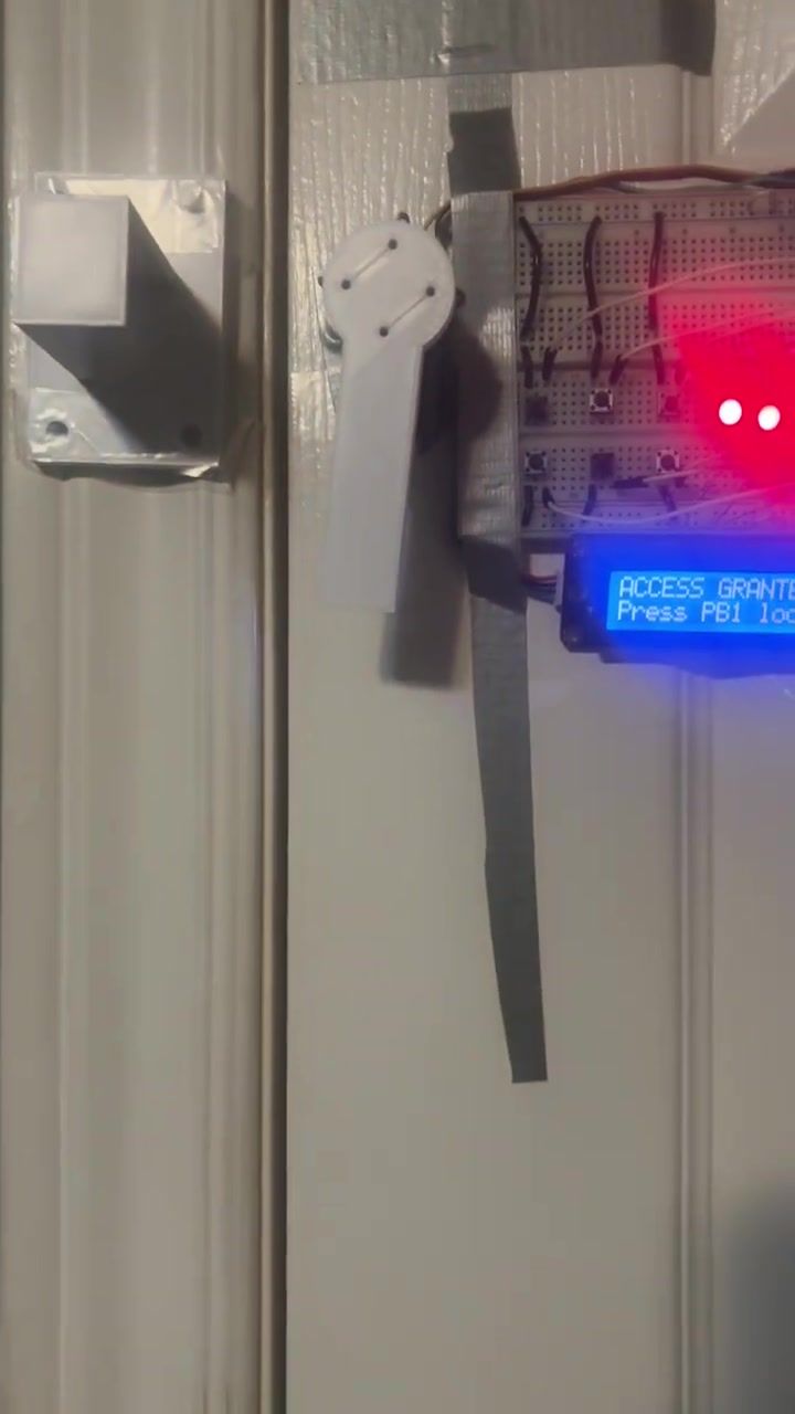 The LCD reading ACCESS GRANTED, Press PB1 to lock, with the servo arm swung out away from the door frame.